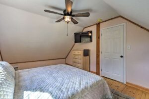 Modern mountain cabin second bedroom with smart tv and fan, on the creek